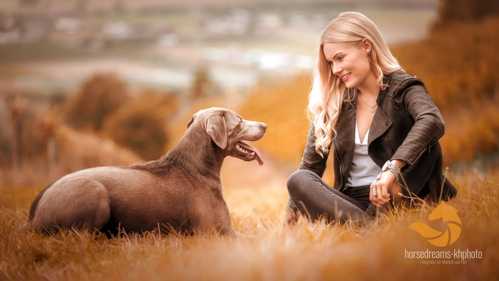 Frau mit ihrem Hund auf einer herbstlichen Wiese